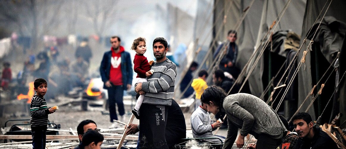 A Syrian refugee holds a baby in a refug...A Syrian refugee hold